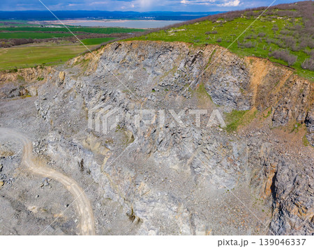 Granite quarry shows rock formations and machinery near a river in the daytime on a clear, sunny day 139046337