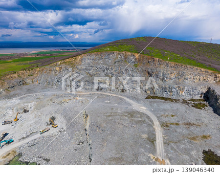Granite quarry in operation with heavy machinery on site and hills in background under a cloudy sky near a landscape view 139046340