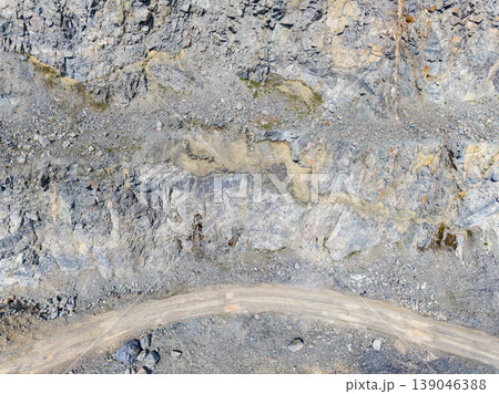 Granite quarry with exposed rock layers and a winding road in a mining site during daylight hours 139046388