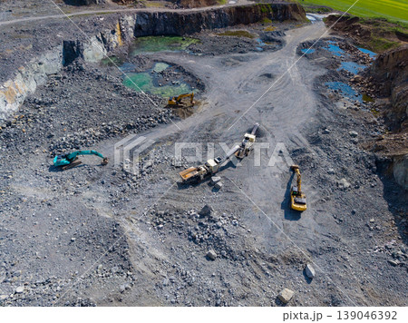 Granite quarry site with machinery and extraction work in operation at a mining location during daytime 139046392