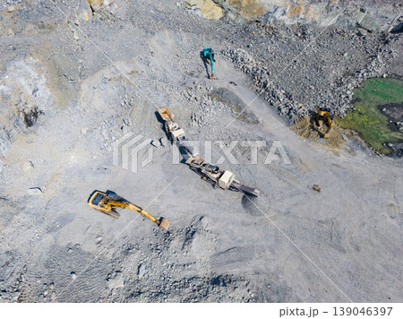 Activity of workers at granite quarry showing machines and tools used at the site for mining and extraction of stone materials in a large open area 139046397