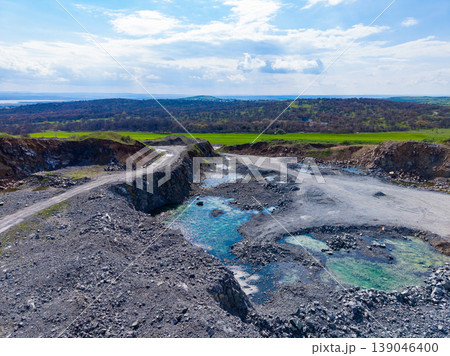 Granite quarry site with rocky terrain and water pools under a cloudy sky during daytime in a rural area Granite quarry site with rocky terrain and water pools under a cloudy sky during daytime in a rural area 139046400