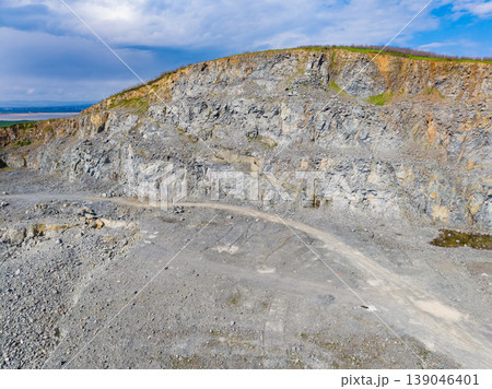 Granite quarry shows large rock formations and clear skies during the day near the coast with no signs of human activity 139046401