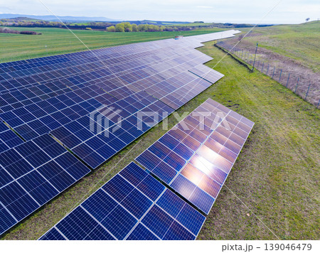 Solar panels cover a large open field with green grass in the background under a clear blue sky during daytime Solar panels cover a large open field with green grass in the background under a clear blue sky during daytime 139046479