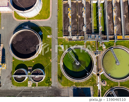 Wastewater treatment facility shows large circular tanks for processing in daytime with clear skies and industrial layout 139046510