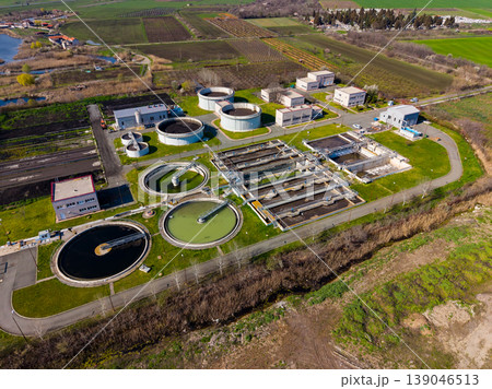 Water treatment facility located near a river with several large tanks and buildings in the landscape during the day Water treatment facility located near a river with several large tanks and buildings in the landscape during the day 139046513