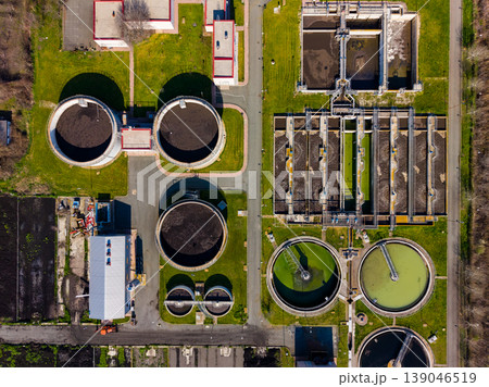 Wastewater treatment facility shows tanks and treatment areas in a structured layout with roads and green spaces around Wastewater treatment facility shows tanks and treatment areas in a structured layout with roads and green spaces around 139046519