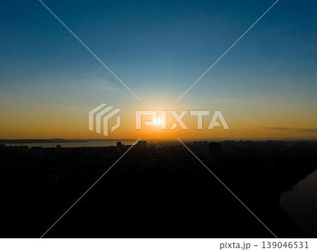 Set sun over city skyline near water in the evening with clear sky and distant buildings visible in the horizon 139046531
