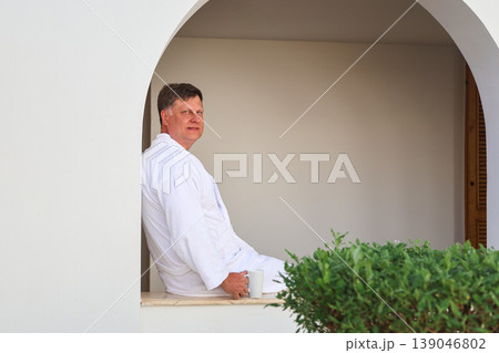 A man on vacation sits in a robe and drinks coffee A man on vacation sits in a robe and drinks coffee 139046802