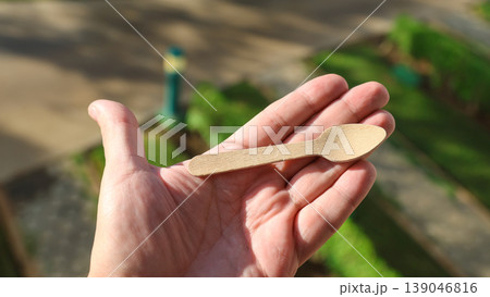 A small eco-friendly wooden spoon in a person's hand 139046816