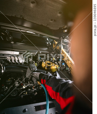 Mechanic repairing car engine in workshop, using tools with dramatic lighting. Automotive maintenance and professional service concept. 139046895