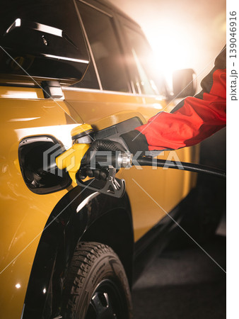 Close-up of fuel nozzle inserted into car tank. Refueling process, automotive energy, transportation and fuel service concept with dramatic lighting. Close-up of fuel nozzle inserted into car tank. Refueling process, automotive energy, transportation and fuel service concept with dramatic lighting. 139046916