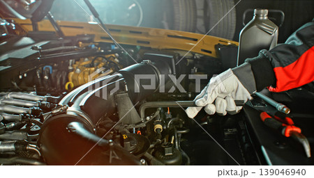 Mechanic repairing car engine in workshop, using tools with dramatic lighting. Automotive maintenance and professional service concept. Mechanic repairing car engine in workshop, using tools with dramatic lighting. Automotive maintenance and professional service concept. 139046940