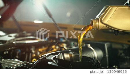 Mechanic pouring engine oil into car engine in workshop. Automotive maintenance, oil change service and professional repair concept with dramatic lighting. Mechanic pouring engine oil into car engine in workshop. Automotive maintenance, oil change service and professional repair concept with dramatic lighting. 139046956