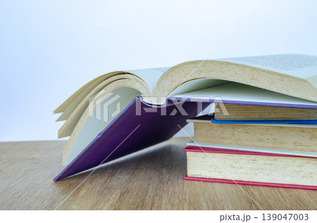 Open book with stacked books on wooden table representing study and research, with customizable space for text. 139047003
