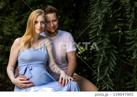 Pregnant young woman and her husband are posing at the gardden. Pregnant young woman and her husband are posing at the gardden. 139047005