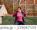 Senior woman doing exercise on outdoor training machines in a park. Healthy lifestyle and vitality in old age. 139047150