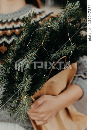 Bouquet of spruce branches with Christmas lights in a female hands. Bouquet of spruce branches with Christmas lights in a female hands. 139047874