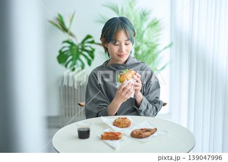 室内でサンドイッチを食べる女性 室内でサンドイッチを食べる女性 139047996