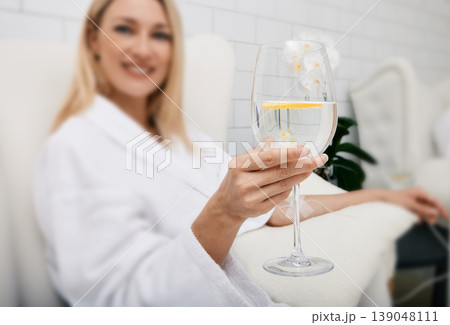 Beautiful woman with glass of refreshing lime drink during intravenous detox therapy with IV drip Infusion. Detox treatments at spa 139048111