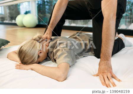 Female patient lying gymnastic mat receiving Yumeiho Japanese back and neck massage with alternative treatment specialist. Therapeutic massage Yumeiho 139048159