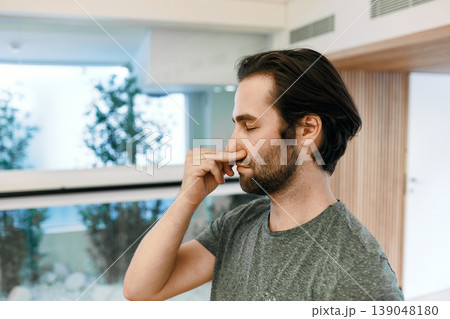 Handsome man practicing yogic breathing technique, pranayama technique and alternating right and left nostril breathing. Yoga breathing exercises 139048180