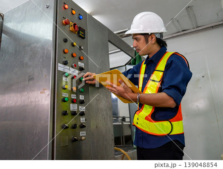 Asian factory technician or engineer hold document file and control the machine by switch and check for it's working in the drinking factory workplace and good industrial. Asian factory technician or engineer hold document file and control the machine by switch and check for it's working in the drinking factory workplace and good industrial. 139048854
