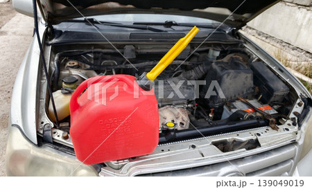 Gas can and car engine scene during a repair task in a garage on a sunny day 139049019