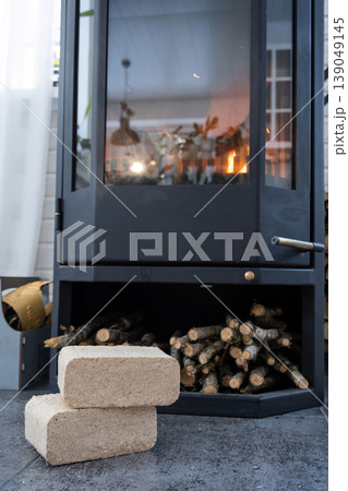Wood fuel briquettes stored near stove, biomass heating source, eco alternative, efficient home heating, crisis and economy-friendly option, sustainable biomass. Wood fuel briquettes stored near stove, biomass heating source, eco alternative, efficient home heating, crisis and economy-friendly option, sustainable biomass. 139049145