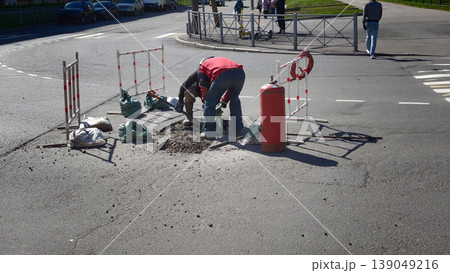 Workers repairing a street at an intersection on a sunny day 139049216