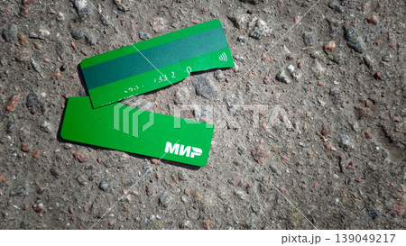 Green payment card lies broken on a dirty street in a busy city 139049217