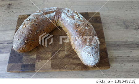 Bread shaped like a crescent resting on a wooden cutting board in a kitchen setting 139049219