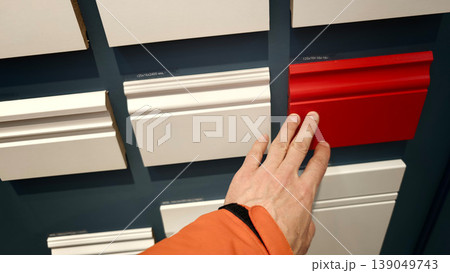 Person touches a red panel among white panels in a display area for home decor 139049743