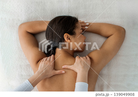 Therapist performing deep tissue massage on upper back of young black woman Therapist performing deep tissue massage on upper back of young black woman 139049908
