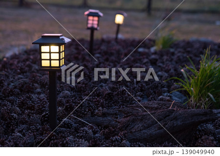 Decorative lantern for flowerbed, solar powered, garden accent lighting, ornamental grasses and mulch, modern landscape design style. Decorative lantern for flowerbed, solar powered, garden accent lighting, ornamental grasses and mulch, modern landscape design style. 139049940