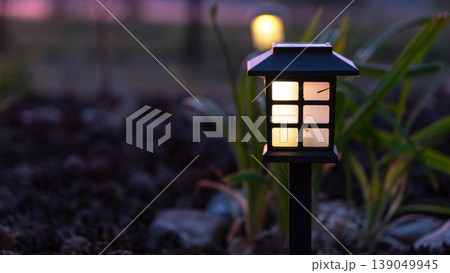 Solar path light in garden bed with grasses and mulch, modern decorative accent, sustainable and stylish outdoor landscape design. Solar path light in garden bed with grasses and mulch, modern decorative accent, sustainable and stylish outdoor landscape design. 139049945