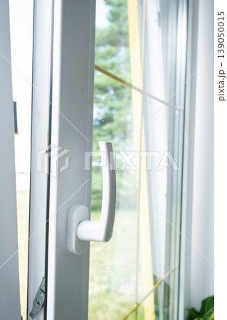 Plastic window handle, window closed, modern PVC profile, proper hardware, importance of ventilation for fresh air, window safety. 139050015