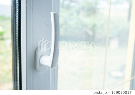 Window handle detail, PVC window closed, focusing on hardware and fittings, efficient insulation, secure closing, prep for ventilation, energy saving. Window handle detail, PVC window closed, focusing on hardware and fittings, efficient insulation, secure closing, prep for ventilation, energy saving. 139050017