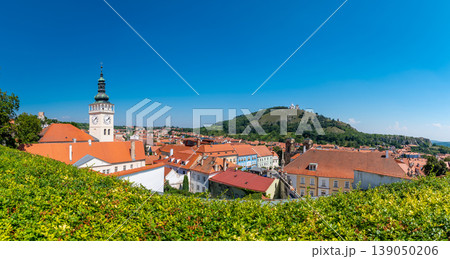 Aerial panorama of Mikulov city, czech republic. The tower of St Wenceslas in foreground. "Svaty kopec" hill with St Sebastian chapel in background. Look to town roofs, summer day. Aerial panorama of Mikulov city, czech republic. The tower of St Wenceslas in foreground. "Svaty kopec" hill with St Sebastian chapel in background. Look to town roofs, summer day. 139050206