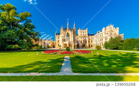 Panoramic view of famous Lednice castle, Czech Republic. Front view with beautiful flowers and green grass. Part of UNESCO heritage. Summer day, with blue sky. Panoramic view of famous Lednice castle, Czech Republic. Front view with beautiful flowers and green grass. Part of UNESCO heritage. Summer day, with blue sky. 139050208
