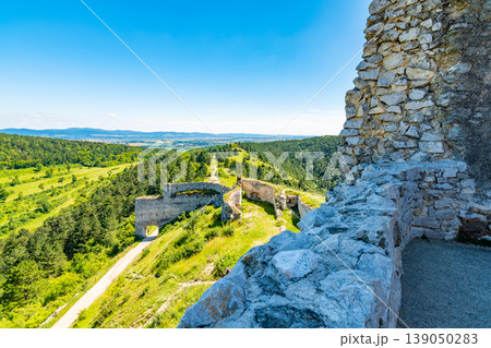 The old ruins of castle Cachtice (Cachtice in local speak). Ruined castle on top of hill at Slovakia. Famous and mysterious place known from legend of blood lady Bathory. Summer day, panorama view. The old ruins of castle Cachtice (Cachtice in local speak). Ruined castle on top of hill at Slovakia. Famous and mysterious place known from legend of blood lady Bathory. Summer day, panorama view. 139050283