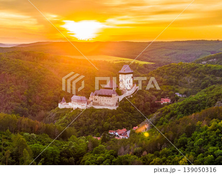 Aerial view of beautiful sunset over the Karlstejn castle, Czech Republic. Drone shot of ancient castle with near forest. Castle in gothic style was build by emperor of Rome rise, Charles IV. Aerial view of beautiful sunset over the Karlstejn castle, Czech Republic. Drone shot of ancient castle with near forest. Castle in gothic style was build by emperor of Rome rise, Charles IV. 139050316