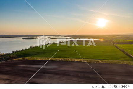 Aerial view of agriculture land at Palava hills, Czech republic. Rural scene near vineyards with power line above dirty road. Summer weather, sunset time. Nove mlyny water lake in background. Aerial view of agriculture land at Palava hills, Czech republic. Rural scene near vineyards with power line above dirty road. Summer weather, sunset time. Nove mlyny water lake in background. 139050408