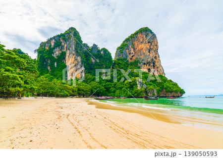 The famous Railay beach at Krabi, Thailand. Long tailed boats are prepared for passengers near limestone rock. Tropical paradise, famous tourist destination. Turquoise sea with white sand The famous Railay beach at Krabi, Thailand. Long tailed boats are prepared for passengers near limestone rock. Tropical paradise, famous tourist destination. Turquoise sea with white sand 139050593