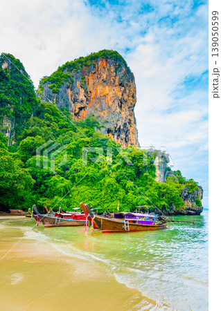 The famous Railay beach at Krabi, Thailand. Long tailed boats are prepared for passengers near limestone rock. Tropical paradise, famous tourist destination. Turquoise sea with white sand The famous Railay beach at Krabi, Thailand. Long tailed boats are prepared for passengers near limestone rock. Tropical paradise, famous tourist destination. Turquoise sea with white sand 139050599