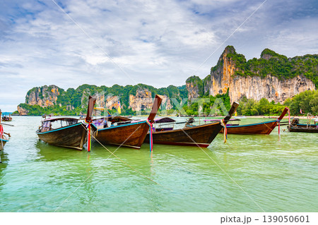 The famous Railay beach at Krabi, Thailand. Long tailed boats are prepared for passengers near limestone rock. Tropical paradise, famous tourist destination. Turquoise sea with white sand The famous Railay beach at Krabi, Thailand. Long tailed boats are prepared for passengers near limestone rock. Tropical paradise, famous tourist destination. Turquoise sea with white sand 139050601