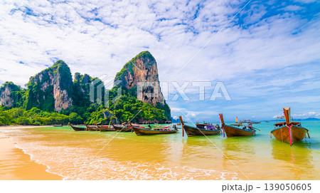 Long tailed boats at famous Railay beach. Boats prepared for tourists from beautiful Thailand beach. Pure blue water with limestone rock above. Tropical paradise, ideal vacation Long tailed boats at famous Railay beach. Boats prepared for tourists from beautiful Thailand beach. Pure blue water with limestone rock above. Tropical paradise, ideal vacation 139050605