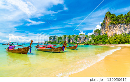 Beautiful view of long tail boats on water in Railay beach bay, Thailand, Krabi town. Famous tourist destination for vacation in tropical paradise. Beautiful summer day. Big limestone hill and rock 139050615