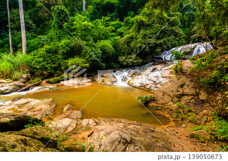 Beautiful waterfall Mae Sa, Thailand. Fresh and pure water stream is flowing on the rock stone ground in tropical rainforest. Fresh plants and trees above river. Vibrant colors in pure nature 139050673
