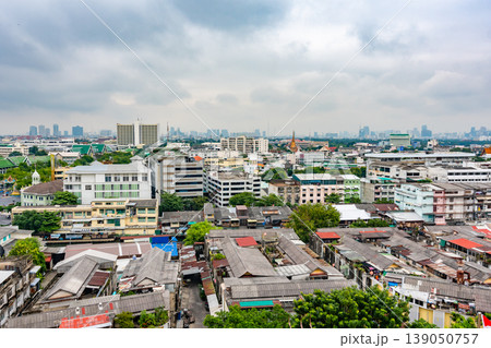 Panorama view of Bangkok city, Thailand. Cityscape of residental buildings in foreground, temples, skyscrapers and modern buildings in far. Fresh trees and plants. Cloudy weather, dramatic clouds. Panorama view of Bangkok city, Thailand. Cityscape of residental buildings in foreground, temples, skyscrapers and modern buildings in far. Fresh trees and plants. Cloudy weather, dramatic clouds. 139050757